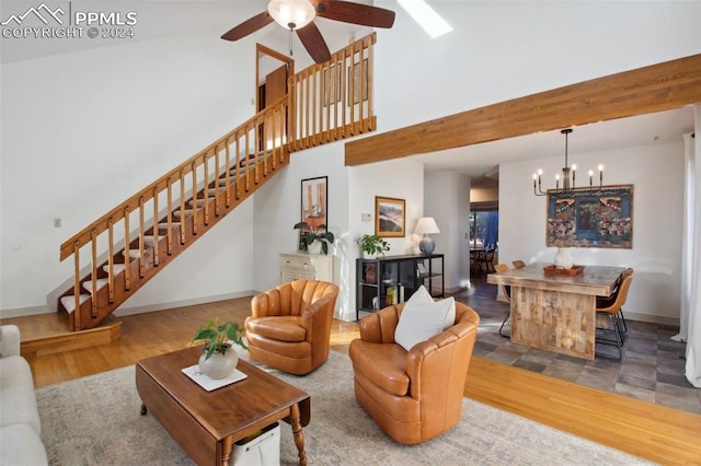 living room with hardwood / wood-style floors, ceiling fan with notable chandelier, and high vaulted ceiling