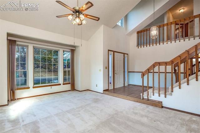 living room with carpet flooring, a textured ceiling, high vaulted ceiling, and ceiling fan with notable chandelier