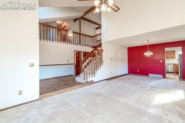 unfurnished living room with carpet flooring, ceiling fan with notable chandelier, beam ceiling, and high vaulted ceiling