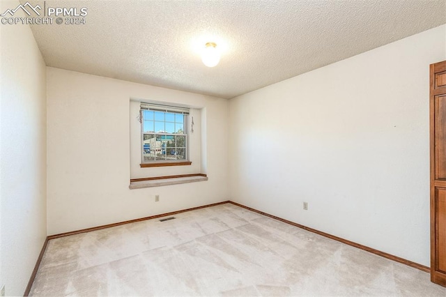 unfurnished room with a textured ceiling and light colored carpet