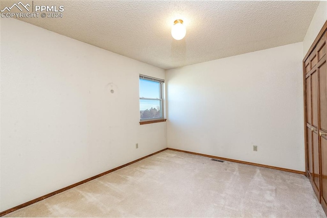 carpeted empty room featuring a textured ceiling