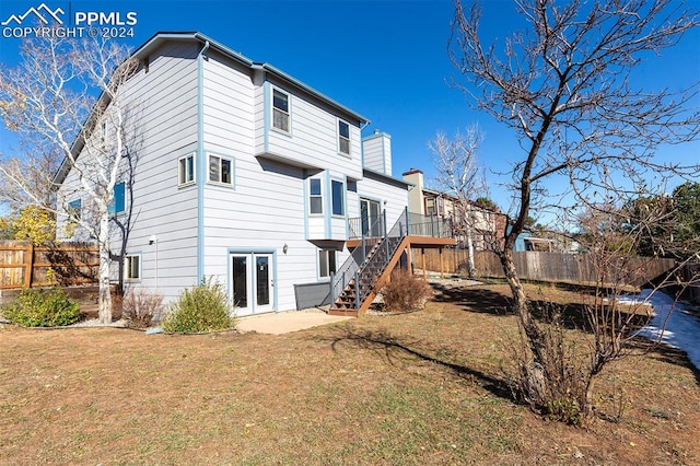 rear view of house featuring french doors, a deck, and a lawn