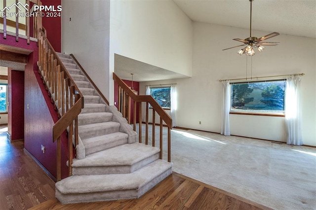 stairway with ceiling fan, hardwood / wood-style floors, and high vaulted ceiling