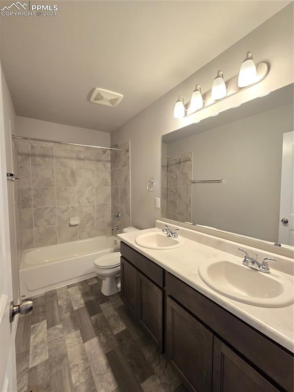 full bathroom featuring tiled shower / bath, toilet, vanity, and hardwood / wood-style flooring