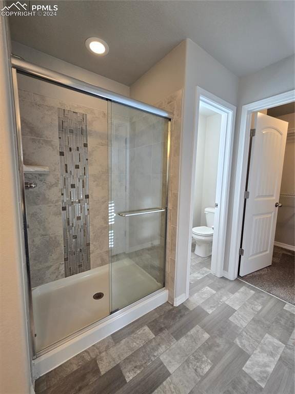 bathroom with toilet and a shower with door