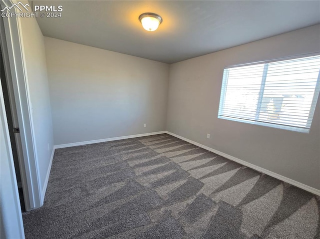 spare room with dark colored carpet