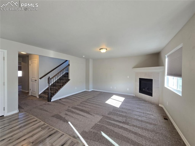 unfurnished living room with carpet and a tile fireplace