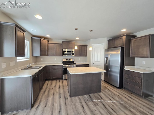 kitchen featuring pendant lighting, a center island, sink, light wood-type flooring, and stainless steel appliances