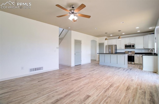 kitchen featuring a center island, appliances with stainless steel finishes, decorative light fixtures, white cabinets, and light wood-type flooring