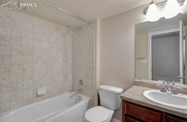 full bathroom with a textured ceiling, vanity, toilet, and tiled shower / bath