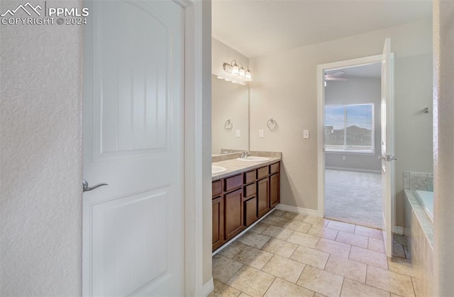 bathroom featuring tile patterned flooring, vanity, and a relaxing tiled tub