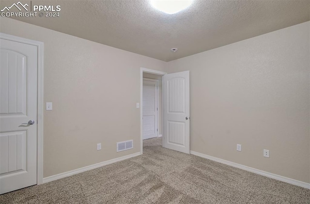 unfurnished room with light colored carpet and a textured ceiling