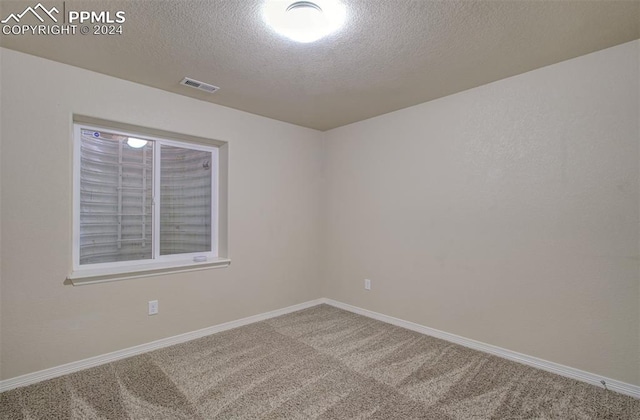 carpeted spare room with a textured ceiling