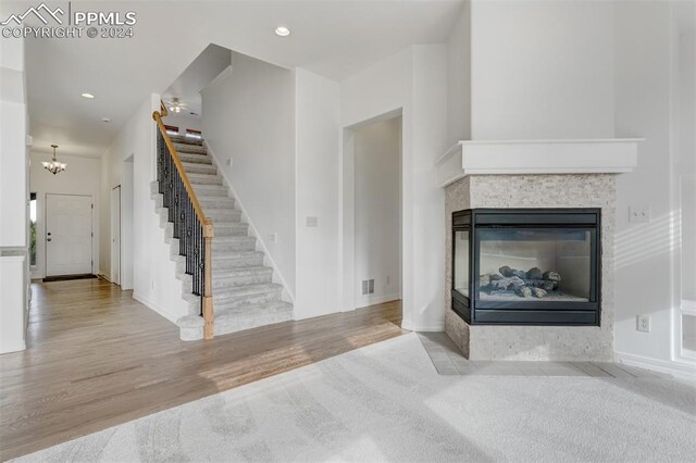 living room with a tile fireplace, light hardwood / wood-style flooring, and an inviting chandelier