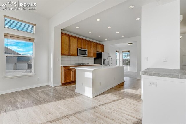 kitchen with decorative backsplash, sink, stainless steel appliances, and light wood-type flooring