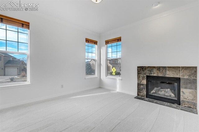 unfurnished living room featuring carpet, crown molding, and a tiled fireplace