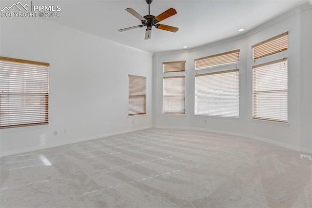 unfurnished room featuring ceiling fan, light colored carpet, and crown molding