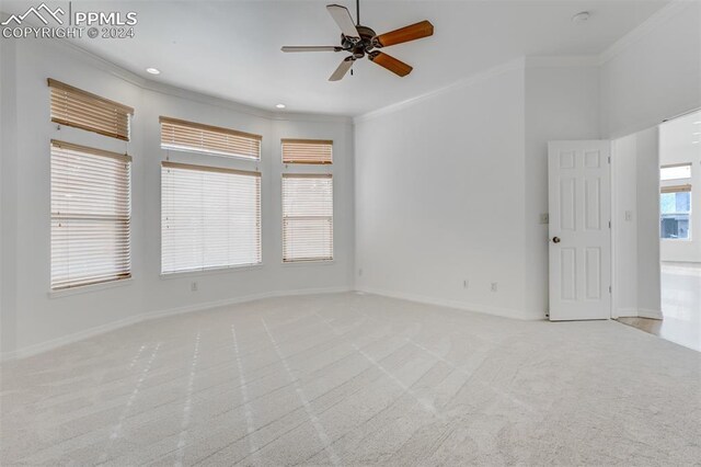 carpeted spare room with ceiling fan and crown molding