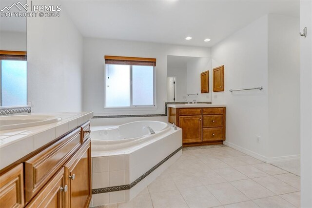 bathroom with tile patterned flooring, vanity, and tiled tub