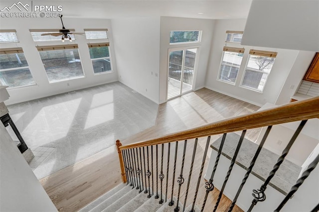 staircase featuring hardwood / wood-style floors, plenty of natural light, and ceiling fan