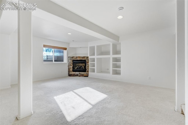 unfurnished living room featuring built in shelves, a fireplace, and light colored carpet