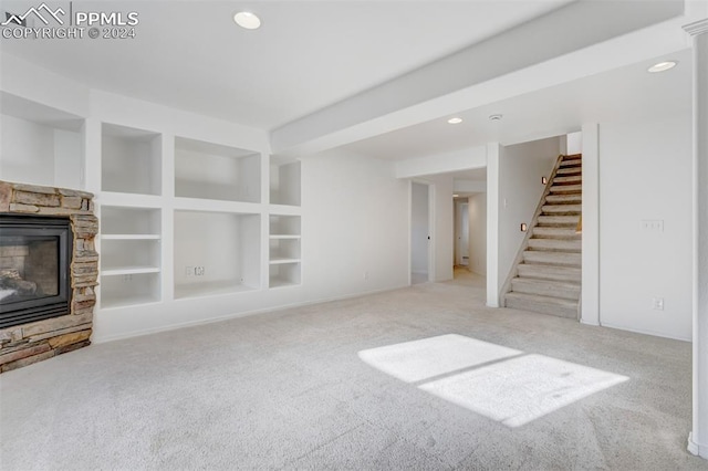 unfurnished living room with a fireplace, built in shelves, and light carpet