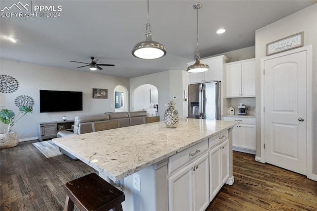 kitchen with stainless steel fridge, a kitchen island, white cabinetry, and dark wood-type flooring