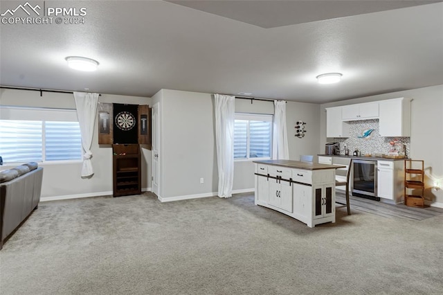 kitchen featuring light colored carpet, white cabinetry, beverage cooler, and tasteful backsplash