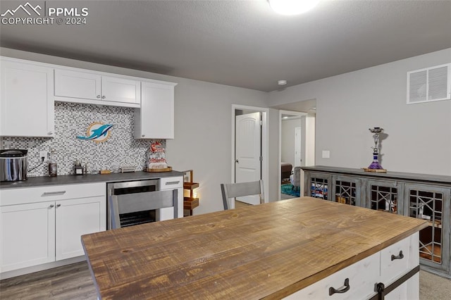 kitchen featuring butcher block countertops, wine cooler, hardwood / wood-style floors, and white cabinets