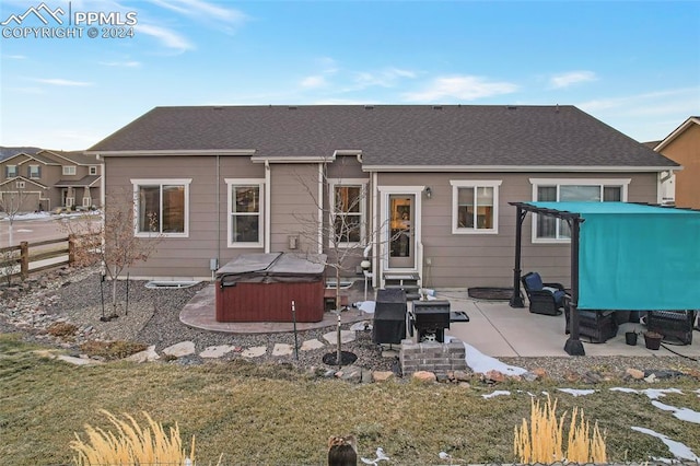 back of property featuring a patio area, a yard, and a hot tub