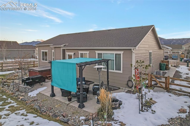 snow covered property with a mountain view, a hot tub, and central AC unit