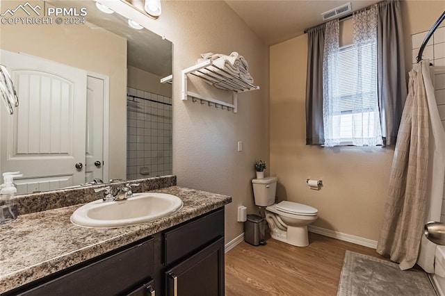 bathroom featuring hardwood / wood-style floors, vanity, curtained shower, and toilet