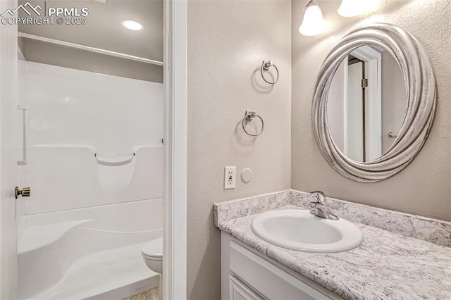 bathroom featuring toilet, a shower, and vanity