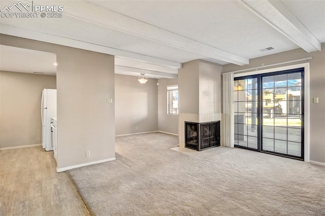 unfurnished living room with a multi sided fireplace, light carpet, and beamed ceiling