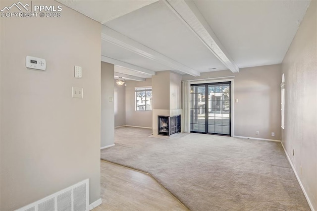 carpeted living room featuring a multi sided fireplace and beamed ceiling