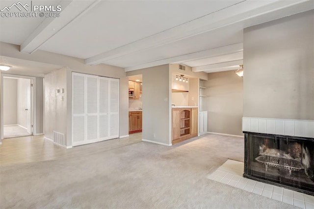 unfurnished living room featuring a tiled fireplace, carpet, and beam ceiling