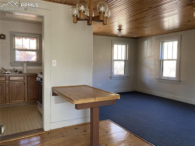 unfurnished dining area featuring wood ceiling, baseboards, and a notable chandelier