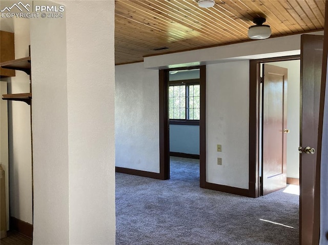 hallway with wooden ceiling, carpet flooring, and baseboards