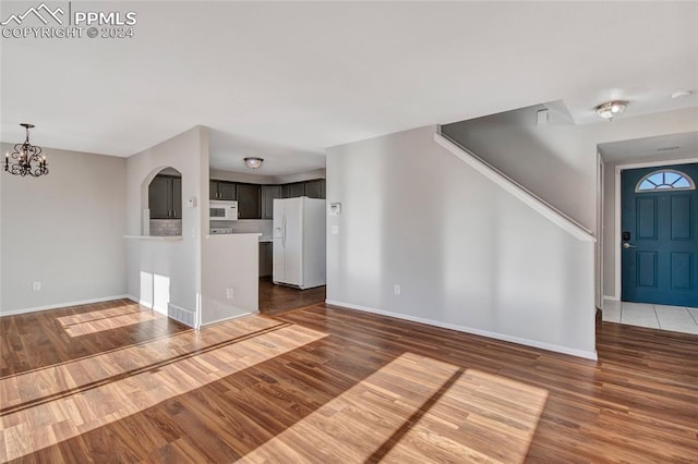 unfurnished living room featuring a notable chandelier and dark wood-type flooring