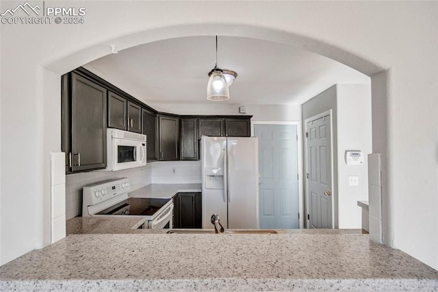 kitchen with decorative light fixtures, light stone countertops, white appliances, and sink