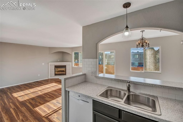 kitchen with dishwasher, sink, dark hardwood / wood-style floors, pendant lighting, and a fireplace