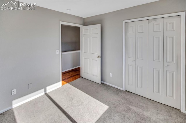 unfurnished bedroom featuring light carpet and a closet