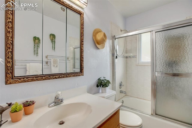 full bathroom featuring toilet, vanity, and combined bath / shower with glass door