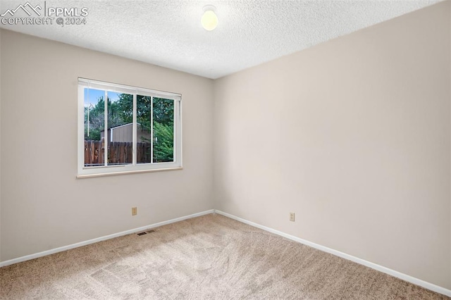 carpeted empty room featuring a textured ceiling