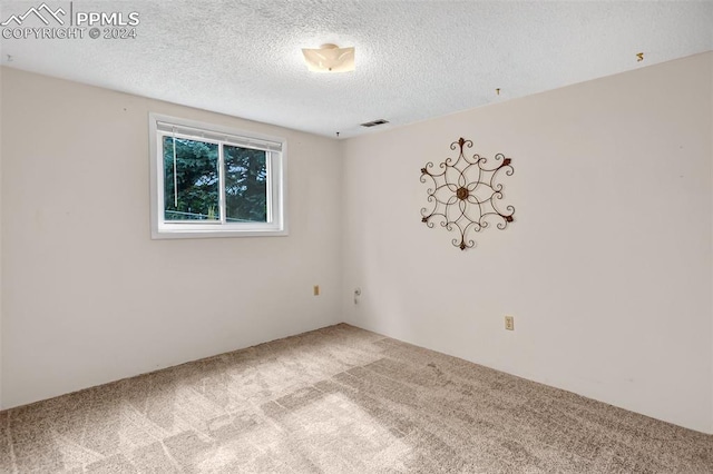 carpeted empty room with a textured ceiling