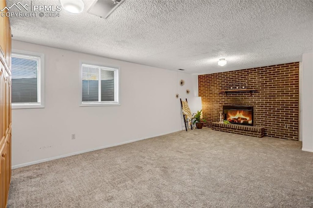 unfurnished living room with carpet flooring, a textured ceiling, and a brick fireplace