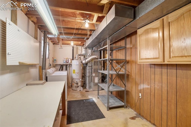 basement with washer and clothes dryer, wood walls, and gas water heater