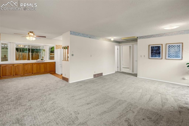 unfurnished living room featuring ceiling fan and light colored carpet