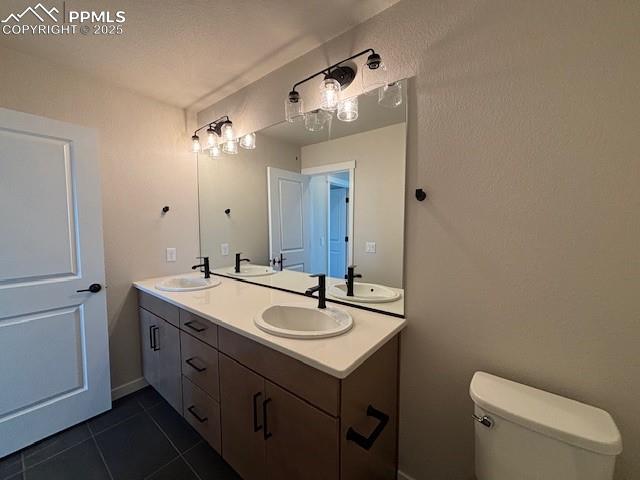 bathroom with double vanity, a sink, and toilet