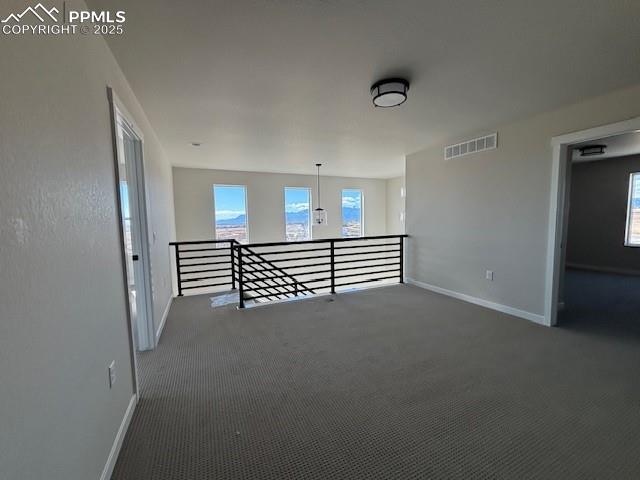 empty room featuring dark carpet, visible vents, and baseboards